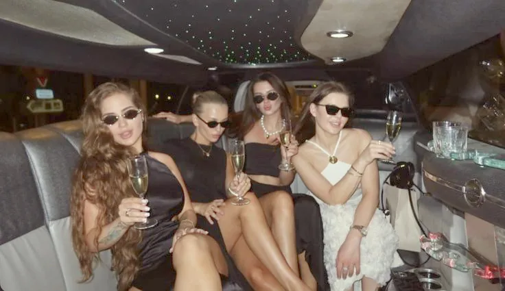Quatre copines en lunettes noires, coupe de champagne à la main, sous le plafond étoilé de l'habitacle