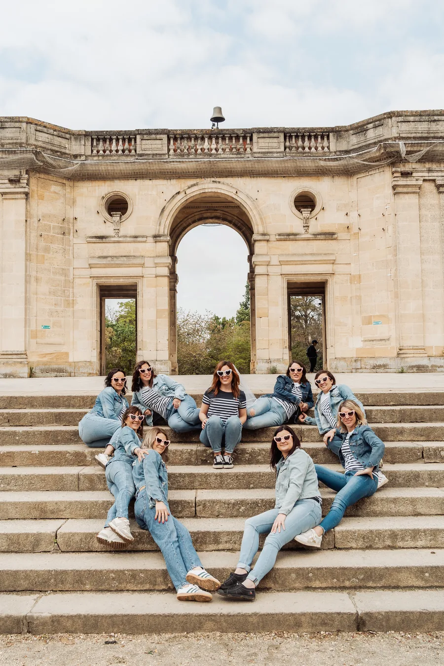 Le groupe assis sur les marches de pierre devant une façade classique à arcade, EVJF à Bordeaux