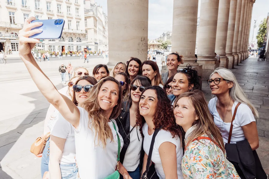 Un selfie pris à bout de bras, le groupe réuni devant une colonnade en ville, EVJF à Bordeaux