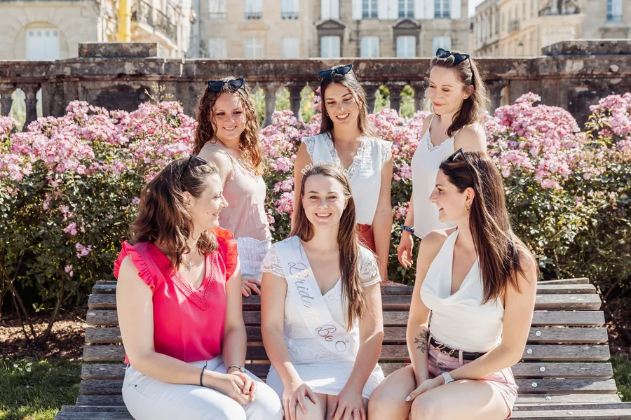 Quatre copines assises devant un massif en fleurs, écharpes de mariée, EVJF à Bordeaux