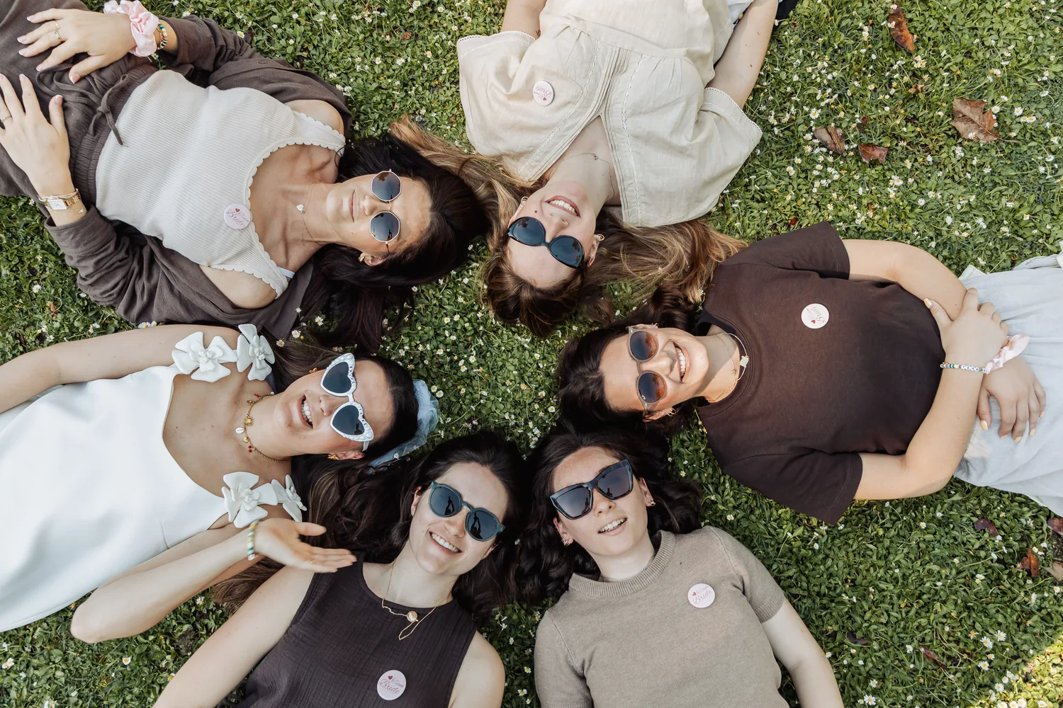 Vue de dessus : les copines allongées en cercle dans l'herbe, têtes au centre, EVJF à Bordeaux