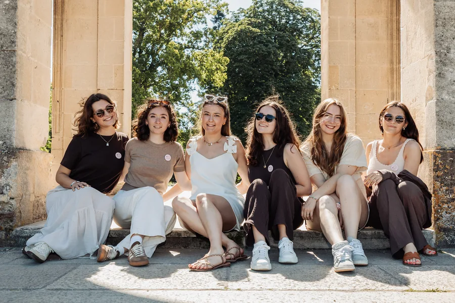 Six amies assises au pied des colonnes, à l'ombre, en tenues claires, EVJF à Bordeaux