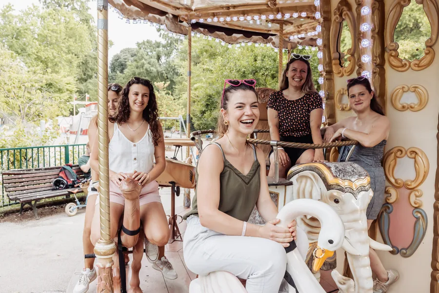Cinq amies installées sur un manège, l'une riant assise sur un cygne, lunettes en cœur roses relevées sur la tête, EVJF à Bordeaux