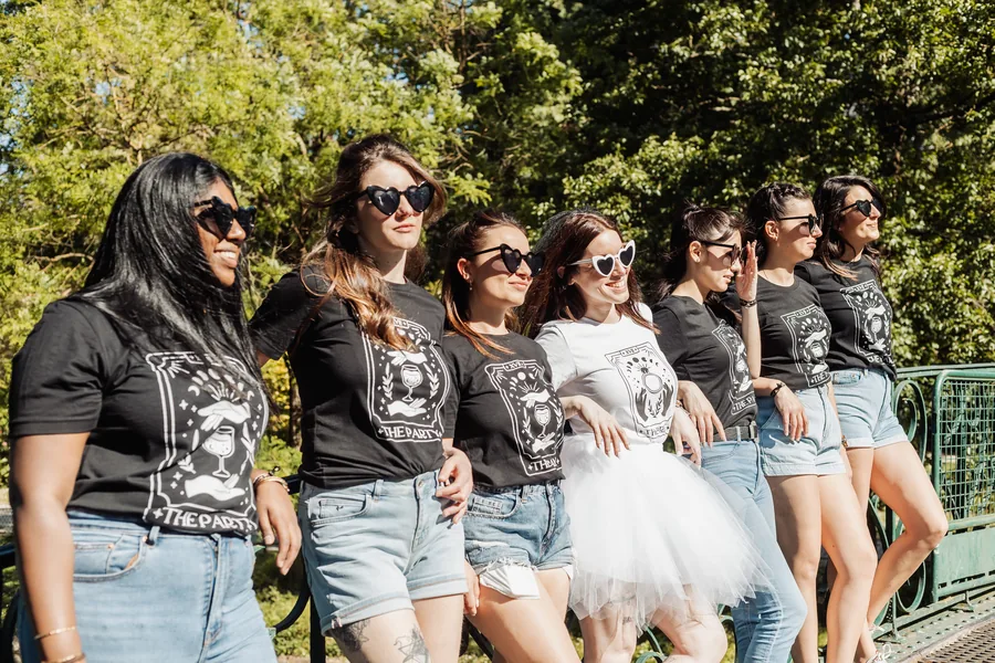 Le groupe en t-shirts imprimés, la mariée en tutu au milieu, dans une allée d'arbres, EVJF à Bordeaux
