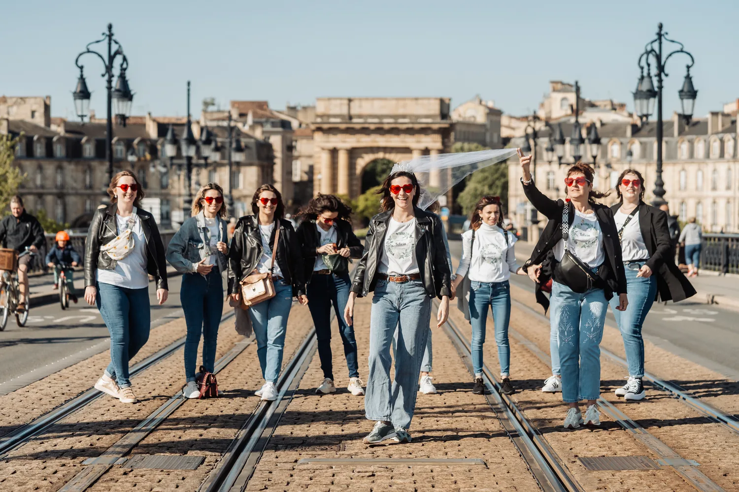 Le groupe qui avance sur les rails du tram, devant une porte de pierre, EVJF à Bordeaux
