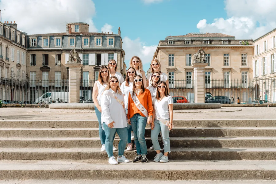 Le groupe sur les marches d'un hôtel particulier, écharpe orange pour la mariée, EVJF à Bordeaux