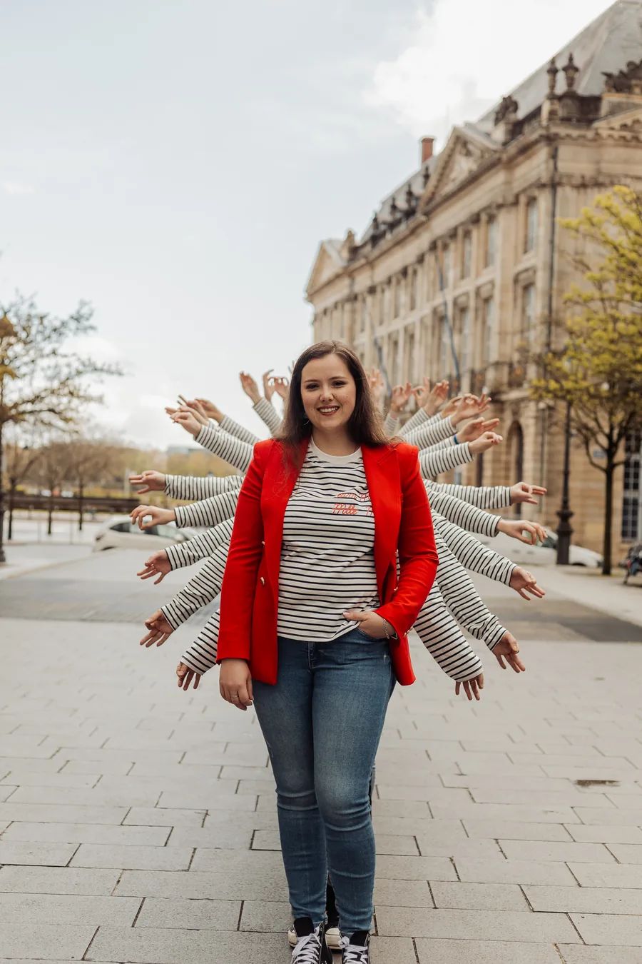 La mariée en veste rouge, les bras de ses amies tendus derrière elle comme des ailes, EVJF à Bordeaux
