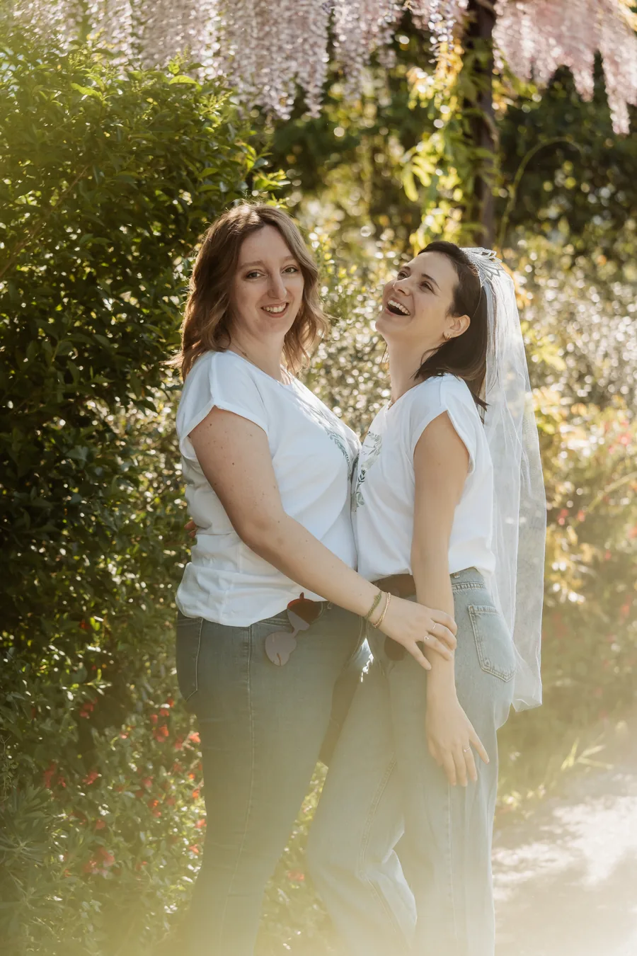 Deux amies qui rient sous la glycine, la mariée voilée tournée vers l'objectif, EVJF à Bordeaux