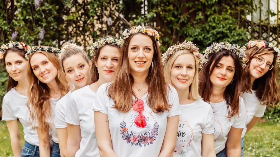 Sept amies en couronnes de fleurs et t-shirts blancs, serrées côte à côte, EVJF à Bordeaux