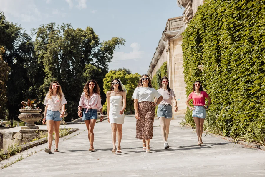 Six copines qui avancent côte à côte dans une allée bordée d'arbres, EVJF à Bordeaux