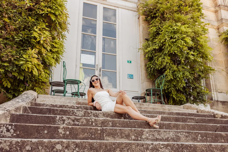 Une copine assise sur un escalier de pierre devant une véranda ombragée, EVJF à Bordeaux