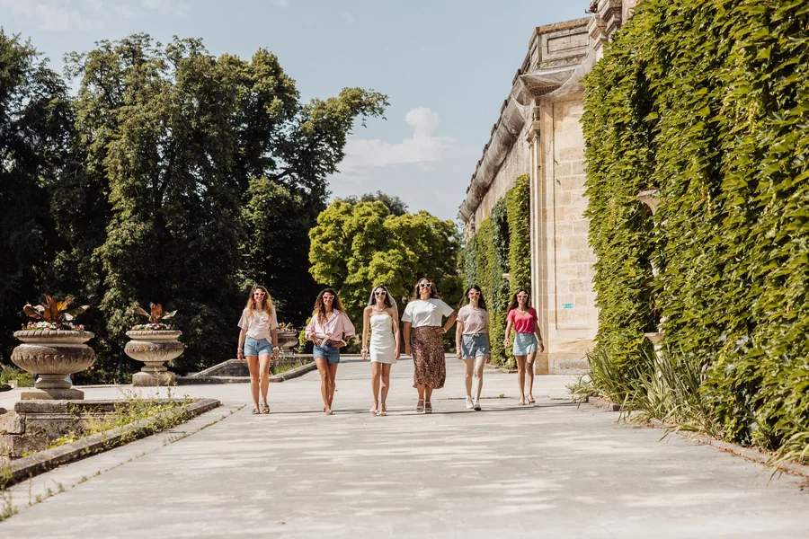 Le groupe qui remonte une allée de jardin, immeubles bordelais en fond, EVJF à Bordeaux