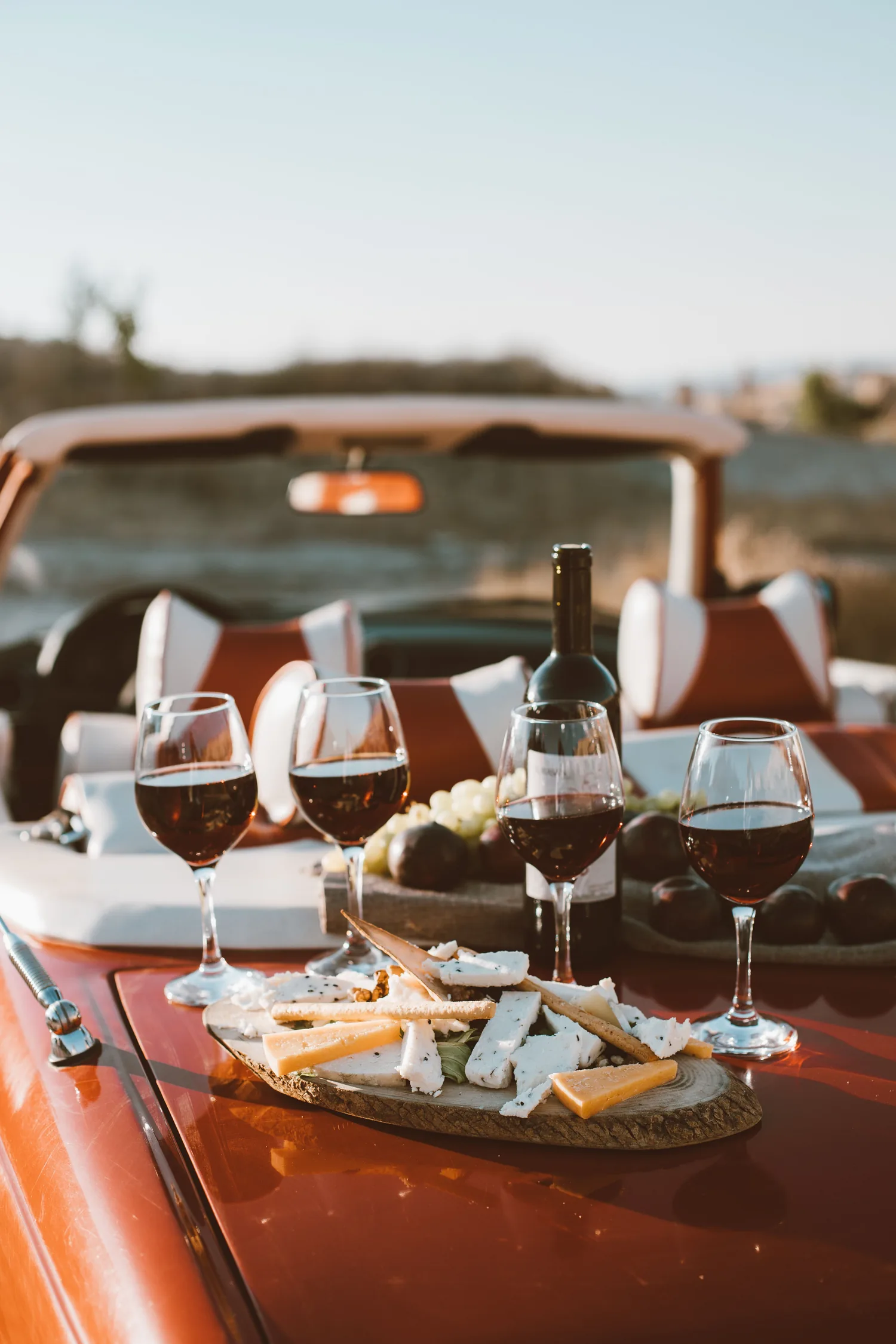Quatre verres de vin rouge, une bouteille et une planche de fromages, posés sur le coffre d'un cabriolet, EVJF à Bordeaux