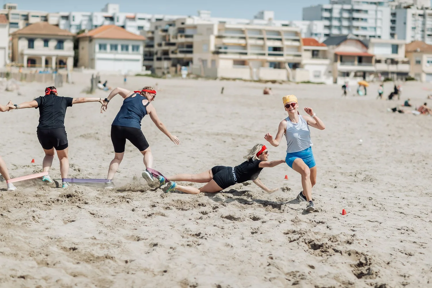 Koh-Bride : une participante en bandana rouge plonge dans le sable pour toucher une adversaire en bandana jaune