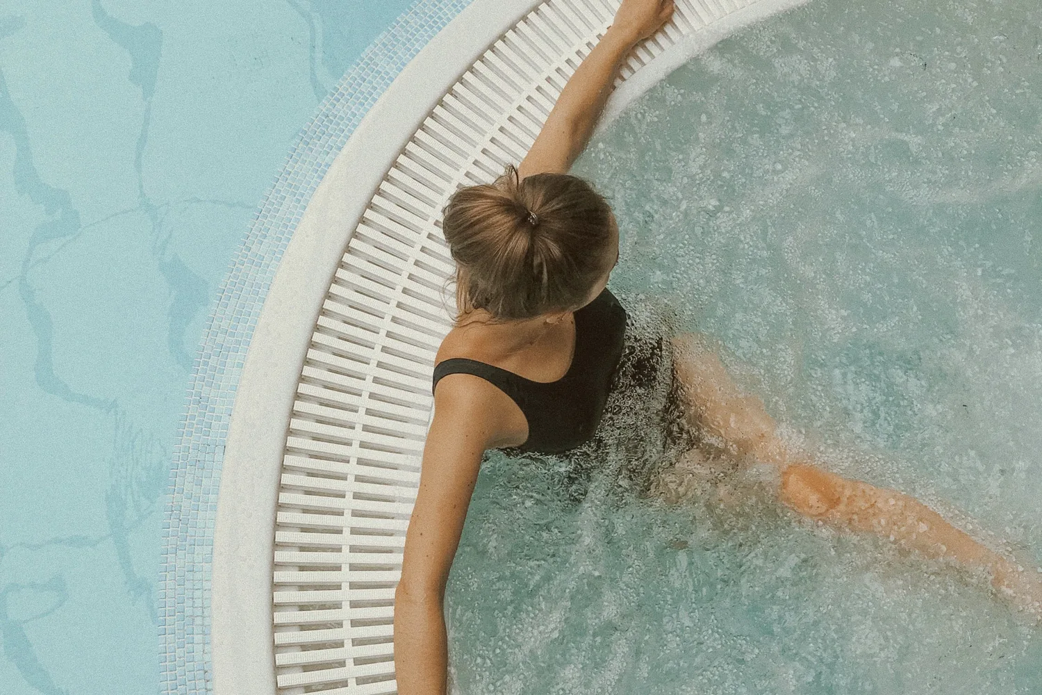 Bain bouillonnant au spa : une femme de dos, les bras posés sur le rebord du bassin